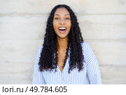 A cheerful young woman with curly hair radiates joy and positivity, leaving a delightful and uplifting atmosphere that is perfectly suited for various lifestyle and wellness themes and topics. A Joyful Young Woman with Curly Hair Smiling Cheerfully Against a Neutral Background. Стоковое фото, агентство Ingram Publishing / Фотобанк Лори