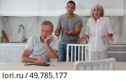Adult man sits at table and thinks how to resolve conflict with his wife and son. Стоковое видео, видеограф Яков Филимонов / Фотобанк Лори