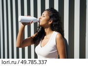 A vibrant and lively woman enjoys a refreshing drink, soaking in the warm sunlight. This moment highlights the vital importance of staying hydrated, prioritizing health and wellness every single day. Enjoy a Refreshing Drink in the Bright Sun A Perfect Blend of Hydration and Wellness. Стоковое фото, агентство Ingram Publishing / Фотобанк Лори