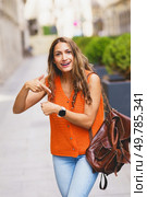 Vertical photo of a latin woman complaining about time pointing her wrist watch outdoors. Woman complaining about time pointing her wrist watch outdoors. Стоковое фото, агентство Ingram Publishing / Фотобанк Лори