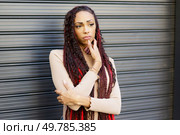 A thoughtful woman with long, beautifully braided hair is striking a pose against a richly textured backdrop, showcasing her unique personal style and selfexpression in a captivating manner. A contemplative woman with beautifully braided hair, situated in a vibrant urban setting. Стоковое фото, агентство Ingram Publishing / Фотобанк Лори