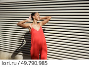 A fashionable woman strikes a confident pose in a stunning red dress, set against a contemporary textured background that perfectly emphasizes her elegance and vibrant style in a dynamic manner. A Stylish Woman Wearing a Stunning Red Dress Posing Elegantly Against a Textured Wall. Стоковое фото, агентство Ingram Publishing / Фотобанк Лори