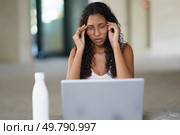 A young woman faces stress and anxiety while working on her laptop, highlighting the challenges of remote work for those advancing their careers in todays fastpaced, competitive, techdriven world. A stressed woman is diligently working on her laptop in a modern and stylish workspace. Стоковое фото, агентство Ingram Publishing / Фотобанк Лори