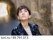 A young woman in a stylish leather jacket stands confidently in an urban setting, gazing thoughtfully upward, capturing a serene moment of introspection amidst the citys vibrant hustle. A Contemplative Young Woman Dressed in a Stylish Leather Jacket Deeply Looking Upwards. Стоковое фото, агентство Ingram Publishing / Фотобанк Лори