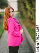 A stylish young woman confidently poses outdoors in a vibrant pink blazer, making a bold statement against a beautifully blurred natural backdrop that enhances her charm and allure. A stylish young woman in a bright pink blazer poses confidently in an outdoor setting. Редакционное фото, агентство Ingram Publishing / Фотобанк Лори