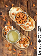 Dried almonds and aromatic almond oil on the table. Almond kernels. Tasty organic almond nuts.. Heap of almond nuts and almond oil. Стоковое фото, агентство Ingram Publishing / Фотобанк Лори