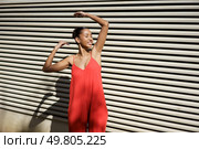 A joyful young woman dances in a vibrant red outfit against a colorful backdrop, radiating happiness, confidence, and zest for life, making the moment captivating and unforgettable. A Joyful Dance Painted in Bright Red Outfit, Set Against an EyeCatching Striped Background. Стоковое фото, агентство Ingram Publishing / Фотобанк Лори