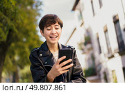 A cheerful young individual interacts with their smartphone against a colorful backdrop of modern architecture, embodying the essence of connectivity and communication in todays fastpaced world. A Young Individual Is Enjoying Their Mobile Phone While In An Urban Setting Today. Стоковое фото, агентство Ingram Publishing / Фотобанк Лори