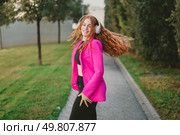 A cheerful woman in a chic pink blazer and comfy headphones dances joyfully on a charming pathway surrounded by lush greenery, radiating happiness, confidence, and distinct personal style. A Stylish Woman in a Bright Pink Blazer Relaxing and Enjoying Music in the Great Outdoors. Стоковое фото, агентство Ingram Publishing / Фотобанк Лори