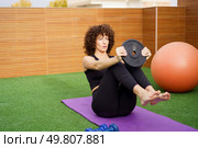 A dedicated woman performs an intense core workout on an outdoor yoga mat with a weight plate, emphasizing the importance of fitness and a healthy lifestyle for overall wellbeing. A dedicated fitness enthusiast is performing an intense core workout utilizing a weight plate. Стоковое фото, агентство Ingram Publishing / Фотобанк Лори