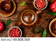 Delicious red tea and pomegranate on table in the teakettle on old wooden rustic background.. Tea With Pomegranate Seeds. Стоковое фото, агентство Ingram Publishing / Фотобанк Лори