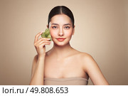 Beauty young woman doing skin care routine, scrapping, massage facial skin with jade gua sha scrapper, Facial treatment for anti aging and cosmetic cleaning. Стоковое фото, агентство Ingram Publishing / Фотобанк Лори