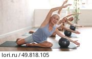 Family grandmother, mother and granddaughter perform fitness exercise sitting on floor with softball. Стоковое видео, видеограф Яков Филимонов / Фотобанк Лори