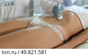 Female patient undergoing ultrasonic cavitation procedure on belly at modern aesthetic medicine clinic to reduce cellulite and adipose fat, improve body shape and reduce circumference. Стоковое видео, видеограф Яков Филимонов / Фотобанк Лори