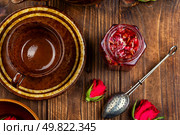 Delicious homemade rose jam in jar with rose flowers with tea utensils on wooden rustic background.. Rose petals homemade jam. Стоковое фото, агентство Ingram Publishing / Фотобанк Лори