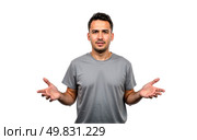 Confused man wearing gray t-shirt standing against white background, looking uncertain, questioning gesture, puzzled expression, open hands, doubtful, casual outfit, isolated on white. Стоковое AI-изображение, AI-художник Павел Муравьев / Фотобанк Лори