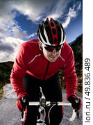 Cyclist on road bike through a asphalt road in the mountains and blue sky with clouds. Стоковое фото, агентство Ingram Publishing / Фотобанк Лори