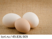 Three eggs on a raffia cloth background. Стоковое фото, агентство Ingram Publishing / Фотобанк Лори