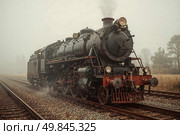 An old steam locomotive from the 19th century stands on the rails. Стоковое AI-изображение, AI-художник Александр Поташев / Фотобанк Лори