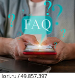 Engaging with FAQ on a smartphone while seated at a desk in a modern workspace. Стоковое фото, фотограф Климов Денис / Фотобанк Лори