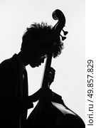 Dark silhouette of a man holding a cello against the light, showcasing the elegant curves of the musical instrument. Стоковое AI-изображение, AI-художник Данила Большаков / Фотобанк Лори