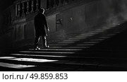 A man is walking up a flight of stairs in the dark, the only source of light guiding his way. Стоковое AI-изображение, AI-художник Данила Большаков / Фотобанк Лори