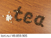 the word "tea" from leaves of green tea on a wooden surface near jasmine flowers. Стоковое фото, агентство Ingram Publishing / Фотобанк Лори