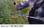 A man with a trimmer mows a garden plot. Стоковое видео, видеограф Igor Skripachev / Фотобанк Лори