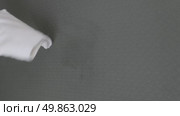 A woman's hand wipes water drops from a black rug with a white cloth. Стоковое видео, видеограф Катерина Белякина / Фотобанк Лори