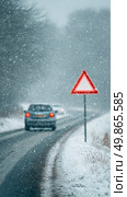 Winter Road Hazard With Warning Triangle and Car in Snowfall on a Remote Highway. Стоковое AI-изображение, AI-художник Юлия Гапеенко / Фотобанк Лори