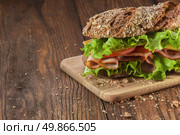 Sandwich on the wooden table with slices of fresh tomatoes, ham, cheese and lettuce. Стоковое фото, агентство Ingram Publishing / Фотобанк Лори