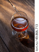 Cognac in glass on the wooden surface. Cognac in glass on the wood. Стоковое фото, агентство Ingram Publishing / Фотобанк Лори