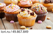 Sweet Temptations: A delightful array of frosted cupcakes with colorful sprinkles for a celebratory treat. Стоковое AI-изображение, AI-художник Данила Большаков / Фотобанк Лори