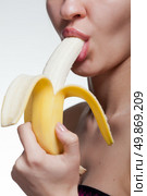 Young woman biting banana isolated on white. Стоковое фото, агентство Ingram Publishing / Фотобанк Лори