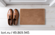 Brown dress shoes placed next to a soft doormat inside a hallway. Стоковое AI-изображение, AI-художник Katsiaryna Repich / Фотобанк Лори