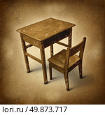 Old school desk symbol of education and learning in simpler times as a bigone old fashined era with vintage wooden student furniture on a dirty background. Стоковое фото, агентство Ingram Publishing / Фотобанк Лори