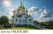 A majestic white Orthodox church with golden domes stands in a park with colorful autumn trees under a blue sky with clouds. Стоковое AI-видео, аниматор Sergey Grishin / Фотобанк Лори