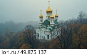 Classic white Orthodox church with golden domes surrounded by bare trees in a foggy park. Peaceful and serene atmospheric scenery, autumn vibes. Стоковое AI-видео, аниматор Sergey Grishin / Фотобанк Лори