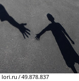 Helping Hand with a shadow on pavement of an adult hand offering help or therapy to a child in need as an education concept of charity towards needy kids and teacher guidance to students who need tutoring. Стоковое фото, агентство Ingram Publishing / Фотобанк Лори
