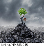 Green businessman concept as a man on top of a mountain heap of garbage holding up a green leaf tree with roots as an environment and conservation icon for waste management or a new healthy beginning. Стоковое фото, агентство Ingram Publishing / Фотобанк Лори