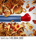 Fitness diet fight concept as a group of unhealthy junk food as hamburgers and fried fast foods being punched open by a person with a boxing glove as a symbol of fighting off cholesterol rich temptation. Стоковое фото, агентство Ingram Publishing / Фотобанк Лори
