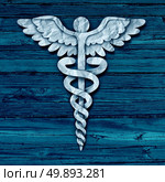 Medical symbol concept as cut crumpled paper shaped as a healthcare treatment icon on old grunge blue wood as a metaphor for hospital care or pharmacy as a photo realistic illustration. Стоковое фото, агентство Ingram Publishing / Фотобанк Лори