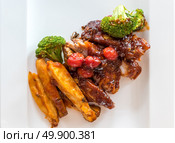 Pork Rib Grilled and Fried Potato Wedges on White Plate with Sauce and Veggies, Gourmet cuisine. Стоковое фото, агентство Ingram Publishing / Фотобанк Лори