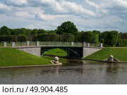 Strelna, St. Petersburg, Russia, June 12, 2025: An openwork bridge over the canal in the Lower Park of the Palace and Park Ensemble of the Konstantinovsky Palace on a sunny summer day. Редакционное фото, фотограф Ula Ulachka / Фотобанк Лори