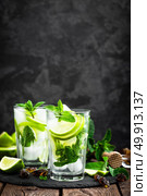 Refreshing mint cocktail mojito with rum and lime, cold drink or beverage with ice on black background. Стоковое фото, агентство Ingram Publishing / Фотобанк Лори