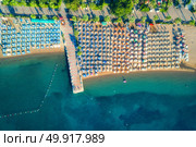 Aerial view of transparent turquoise sea, beautiful sandy beach with colorful chaise-lounges, boats, green trees, hotels, buildings at sunrise in Icmeler,Turkey. Summer seascape Top view from drone. Aerial view of transparent turquoise sea. Стоковое фото, агентство Ingram Publishing / Фотобанк Лори