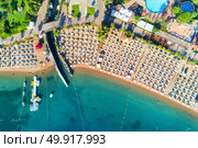 Aerial view of transparent turquoise sea, beautiful sandy beach with colorful chaise-lounges, boats, green trees, pool, hotels, buildings at sunrise in Icmeler, Turkey. Summer landscape. Top view.. Aerial view of Icmeler, Turkey. Стоковое фото, агентство Ingram Publishing / Фотобанк Лори