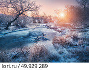 Winter forest with amazing river at sunset. Winter landscape with snowy trees, ice, beautiful frozen river, snowy bushes, colorful sky in dusk. Blurred water. Small waterfalls.Creek with water cascade. Winter landscape with snowy trees, ice, beautiful frozen river. Стоковое фото, агентство Ingram Publishing / Фотобанк Лори