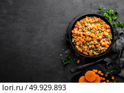 Carrot braised with fresh green peas in creamy milk sauce in stewpan, vegetable saute on black background, top view. Стоковое фото, агентство Ingram Publishing / Фотобанк Лори