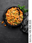 Carrot braised with fresh green peas in creamy milk sauce in stewpan, vegetable saute on black background, top view. Стоковое фото, агентство Ingram Publishing / Фотобанк Лори